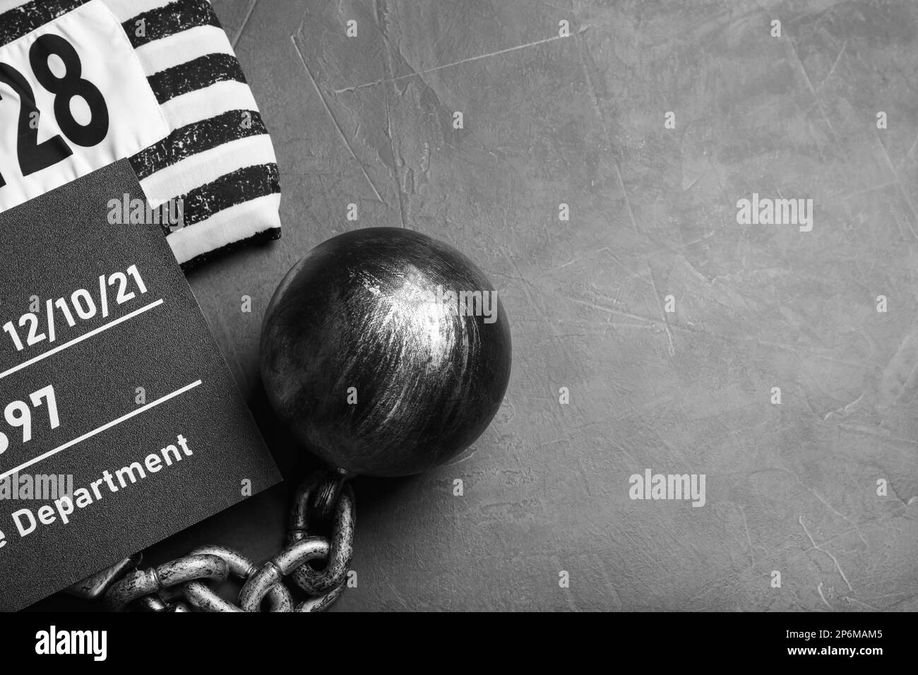 Metal ball with chain, prison uniform and mugshot letter board on grey table, flat lay. Space for text Stock Photo