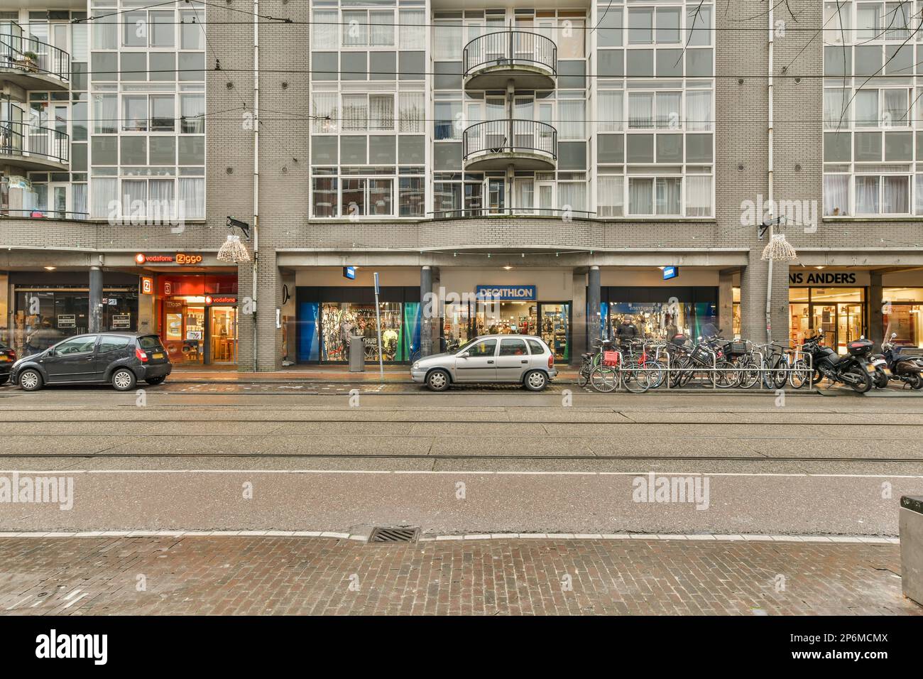 a city street with cars parked on the side and people walking down the ...