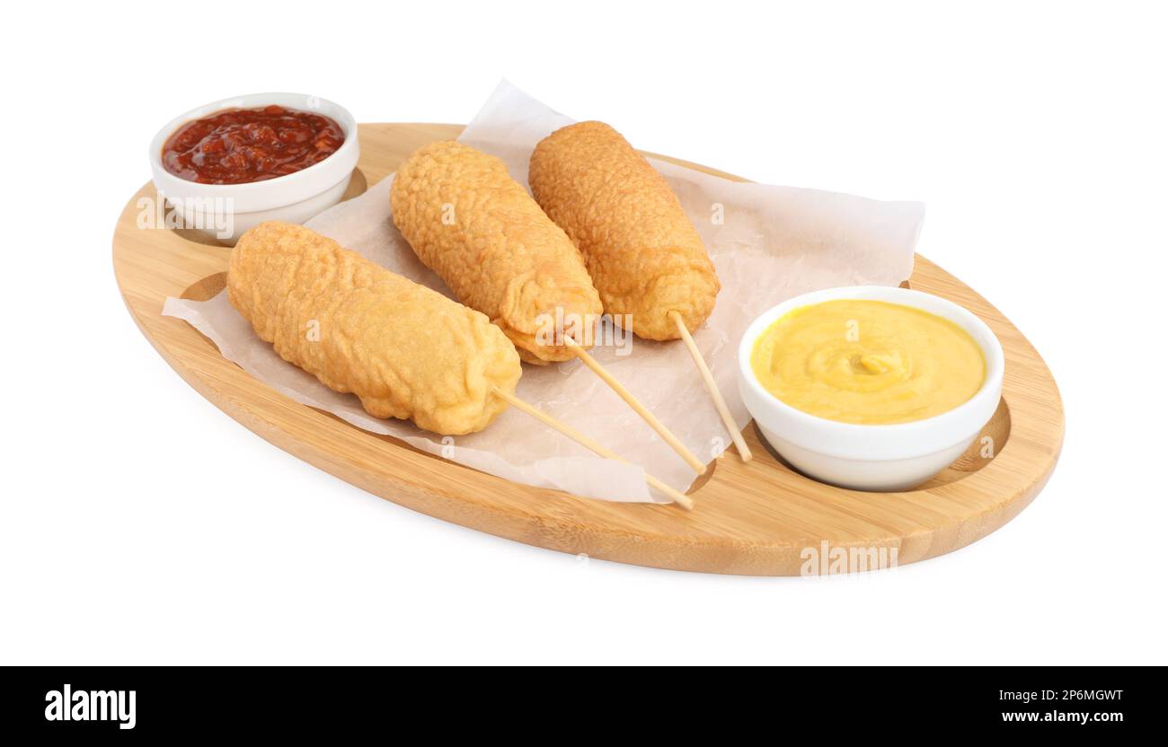 Delicious deep fried corn dogs with board and sauces isolated on white