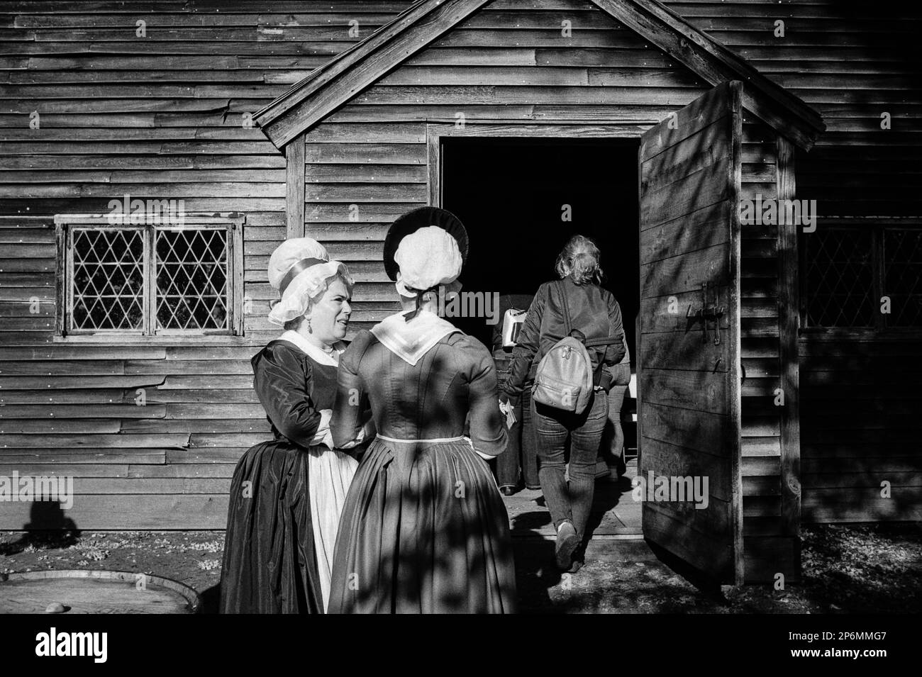 An actress dressed as Martha Washington stands with a counterpart as a tourist enters the meeting house during a Revolutionary War reenactment at the Stock Photo