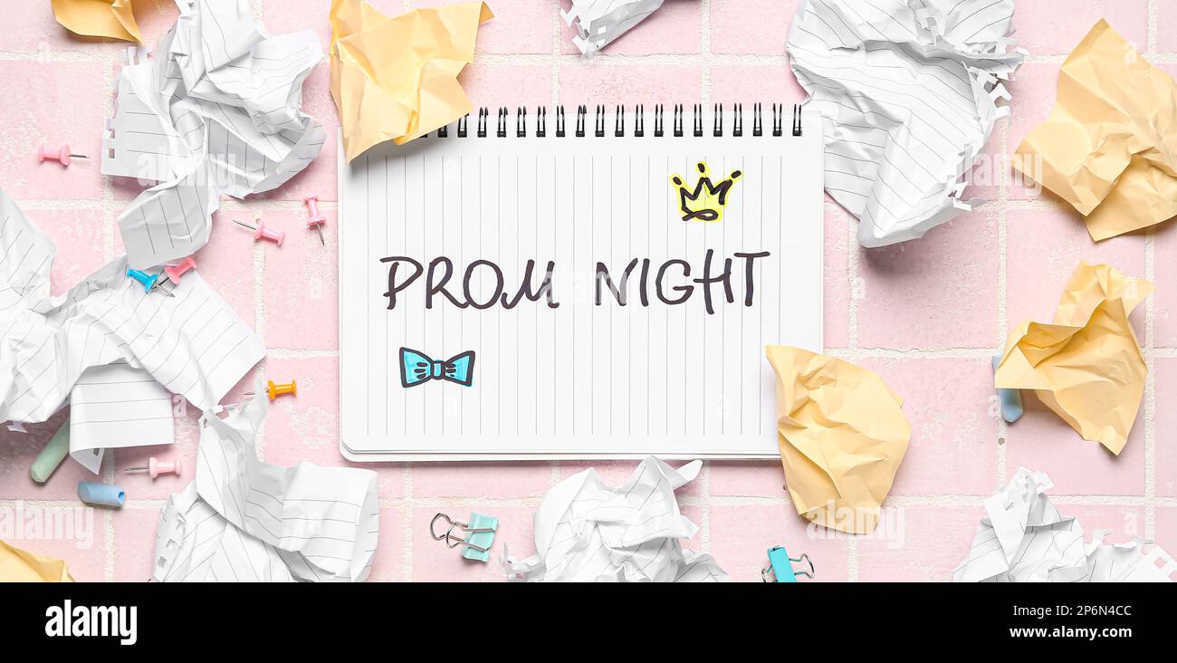 Notebook with text PROM NIGHT and crumpled paper sheets on pink tile background Stock Photo