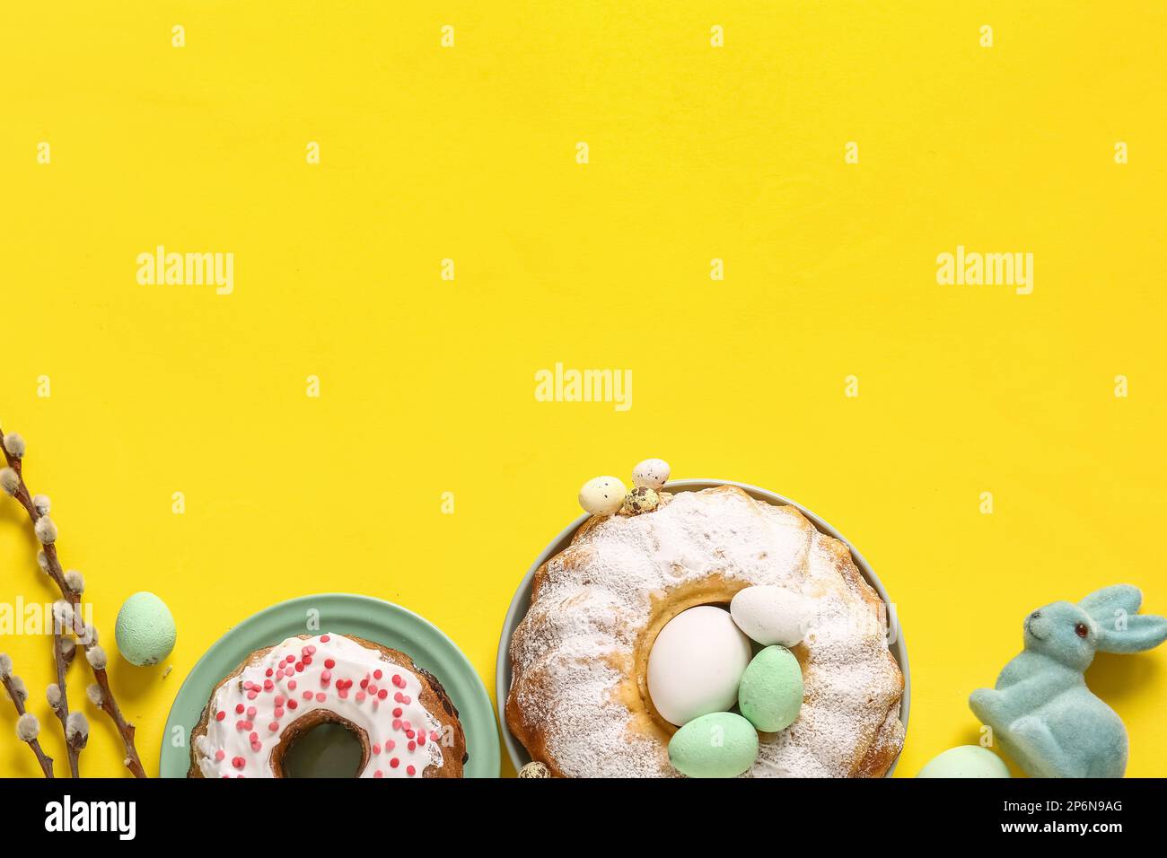 Composition with tasty Easter cakes and eggs on yellow background Stock Photo
