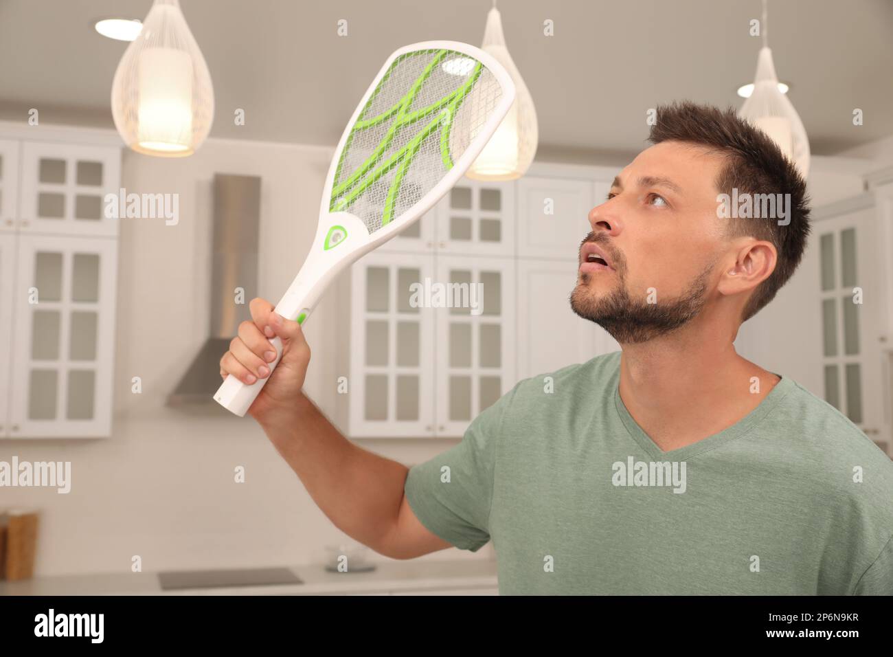 Man with electric fly swatter in kitchen. Insect killer Stock Photo Alamy