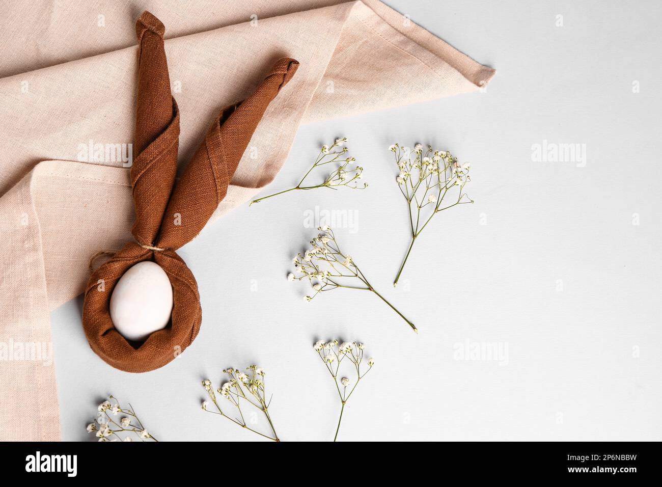 Composition with Easter egg wrapped in napkin and gypsophila flowers on ...