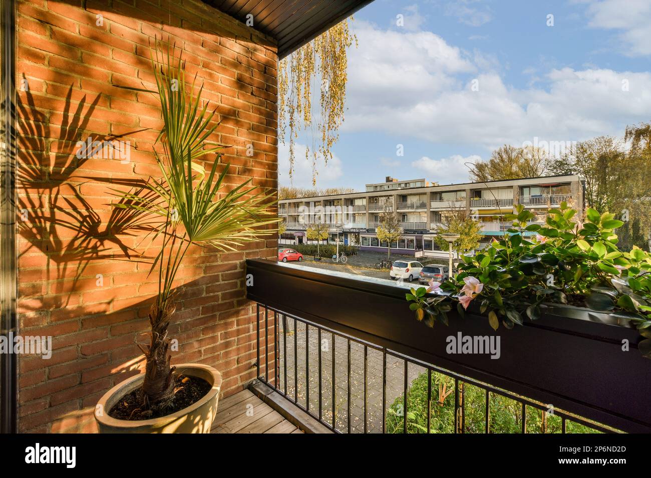 a balcony with plants on the railing and buildings in the background