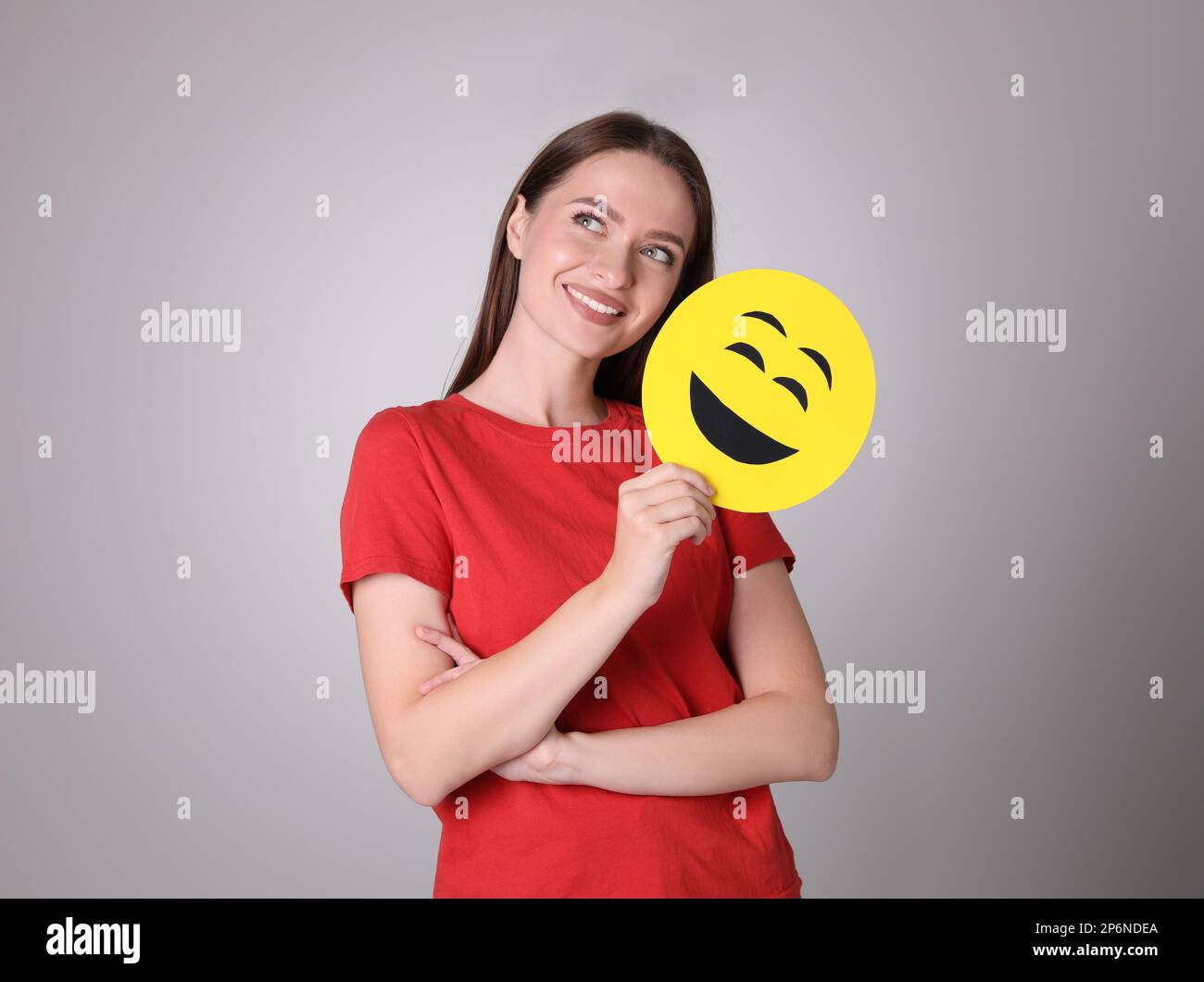 Happy young woman with laughing emoji on grey background Stock Photo ...