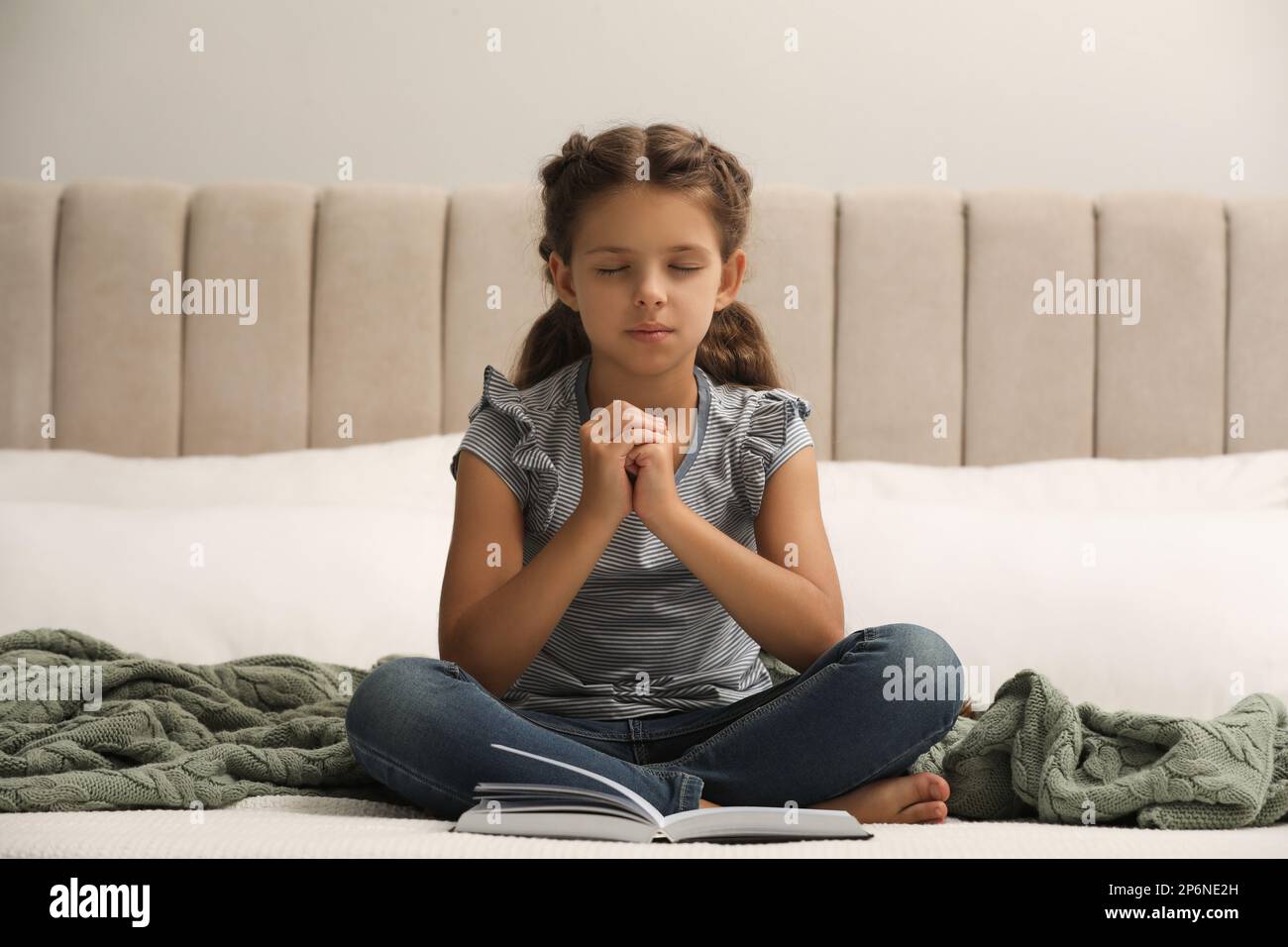 Cute little girl praying over Bible in bedroom Stock Photo Alamy