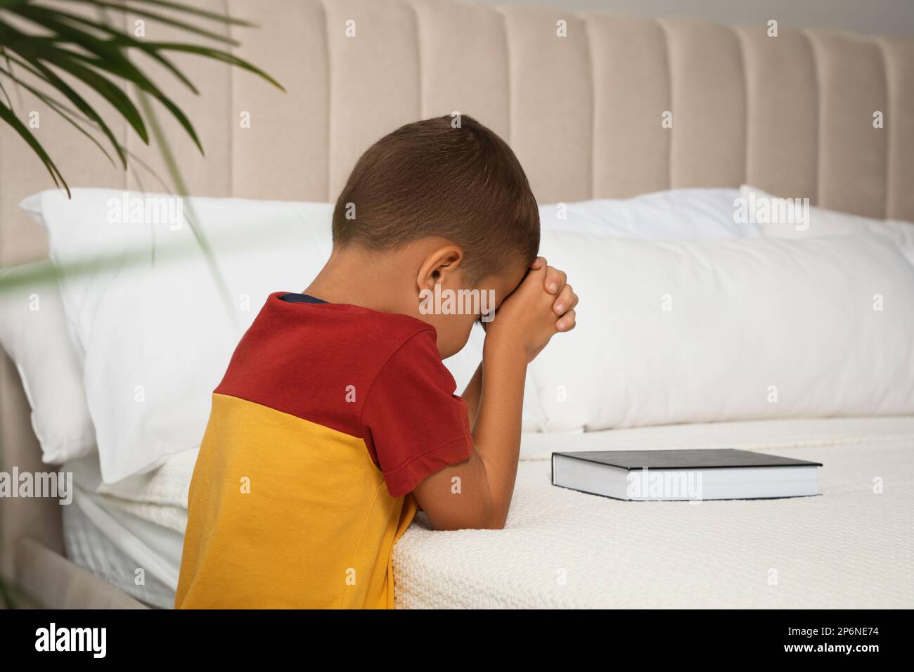 Cute little boy with hands clasped together saying bedtime prayer over ...