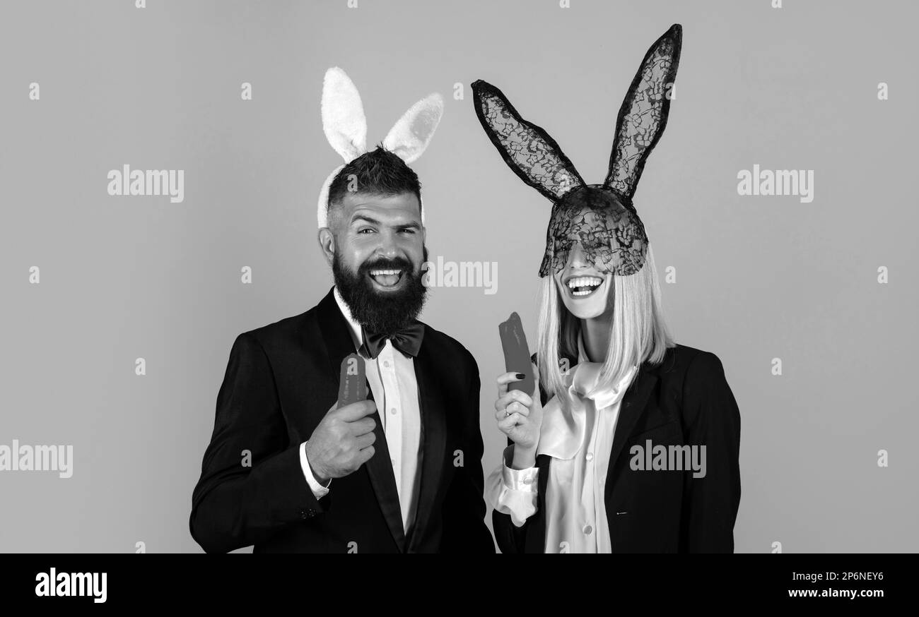 Easter bunny couple eat carrot. Funny couple wearing bunny ears. Bunny