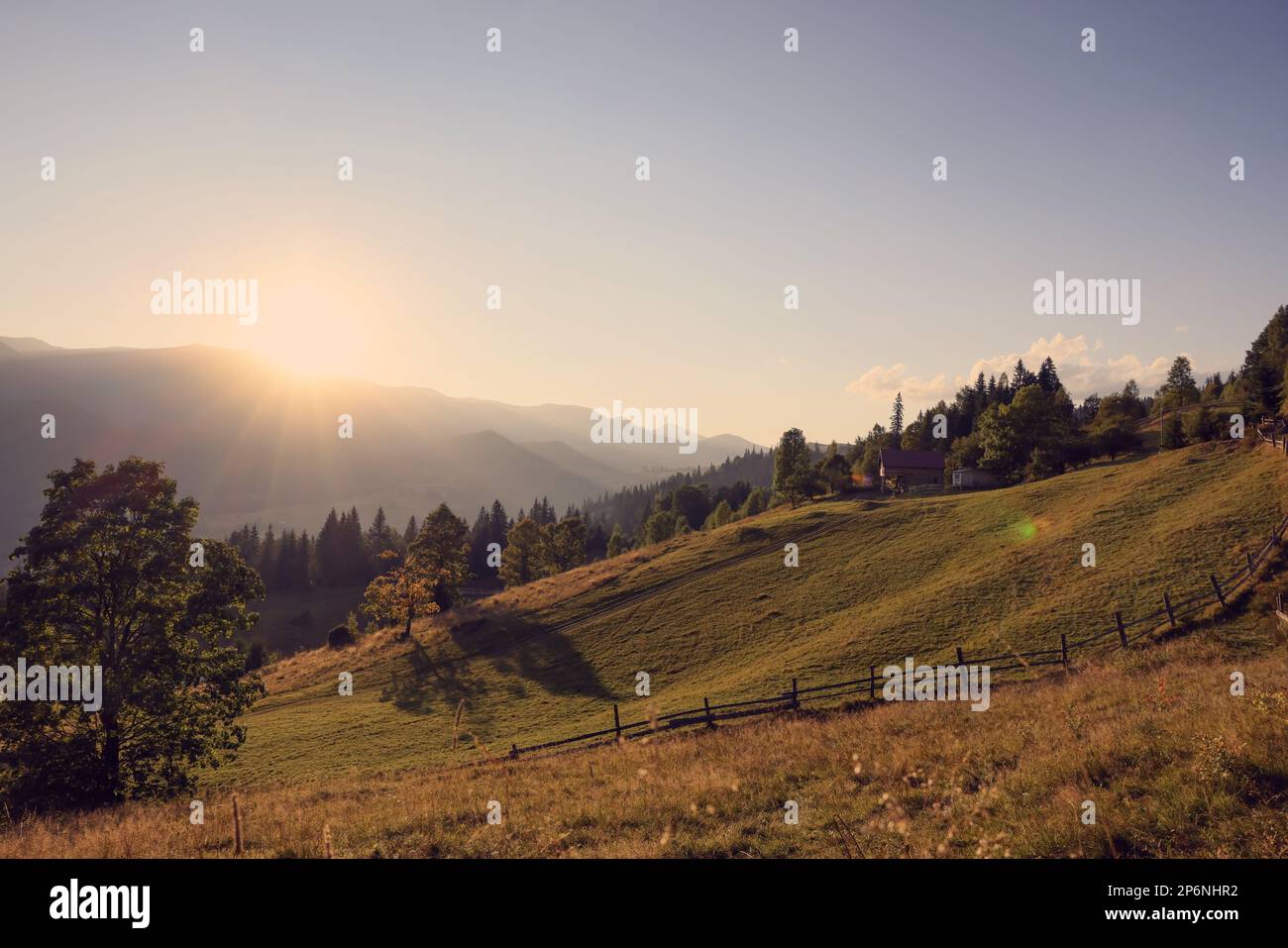 Morning sun shining over pasture in mountains Stock Photo