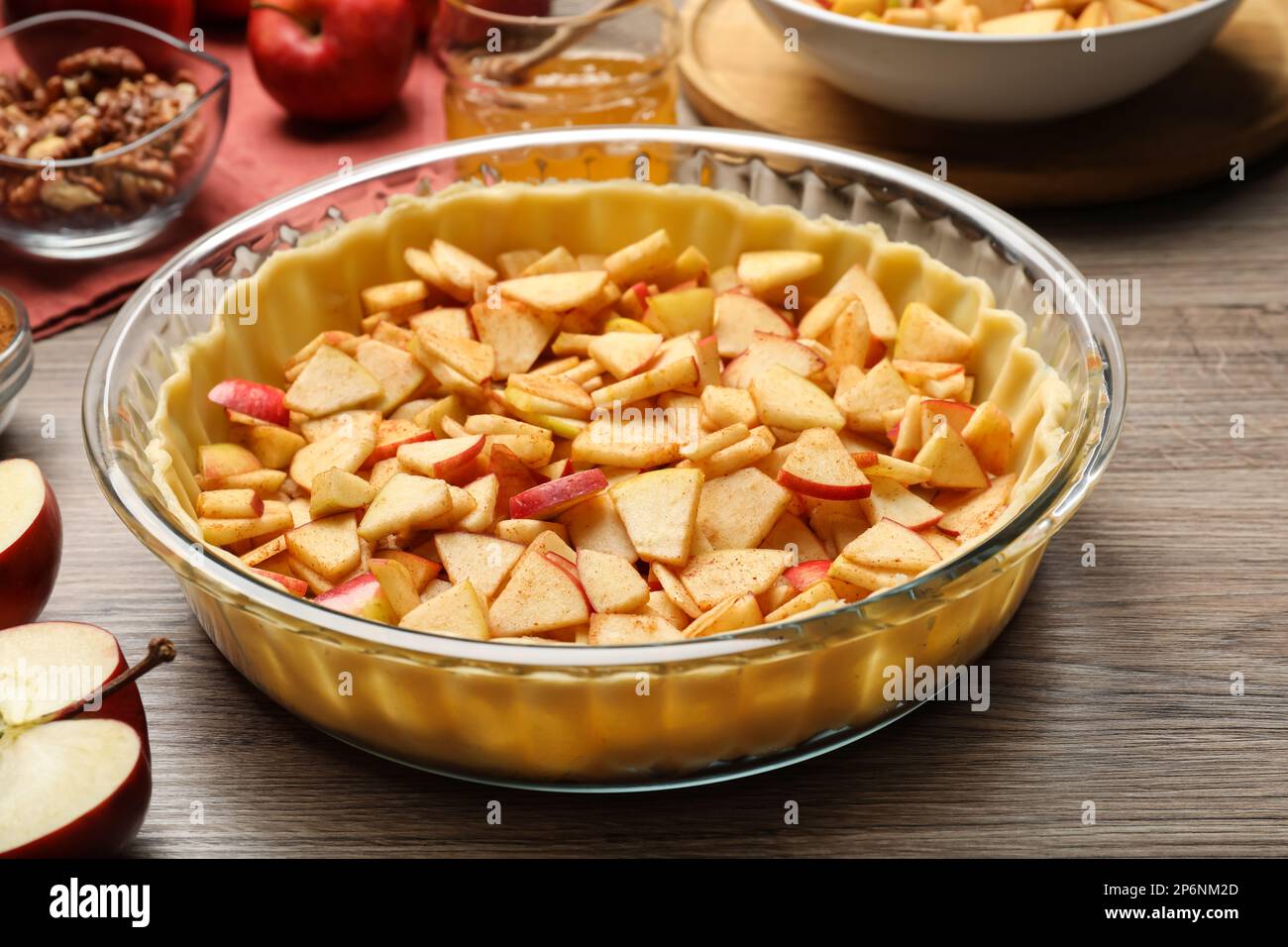 Raw dough with apple slices on wooden table, closeup. Baking pie Stock Photo