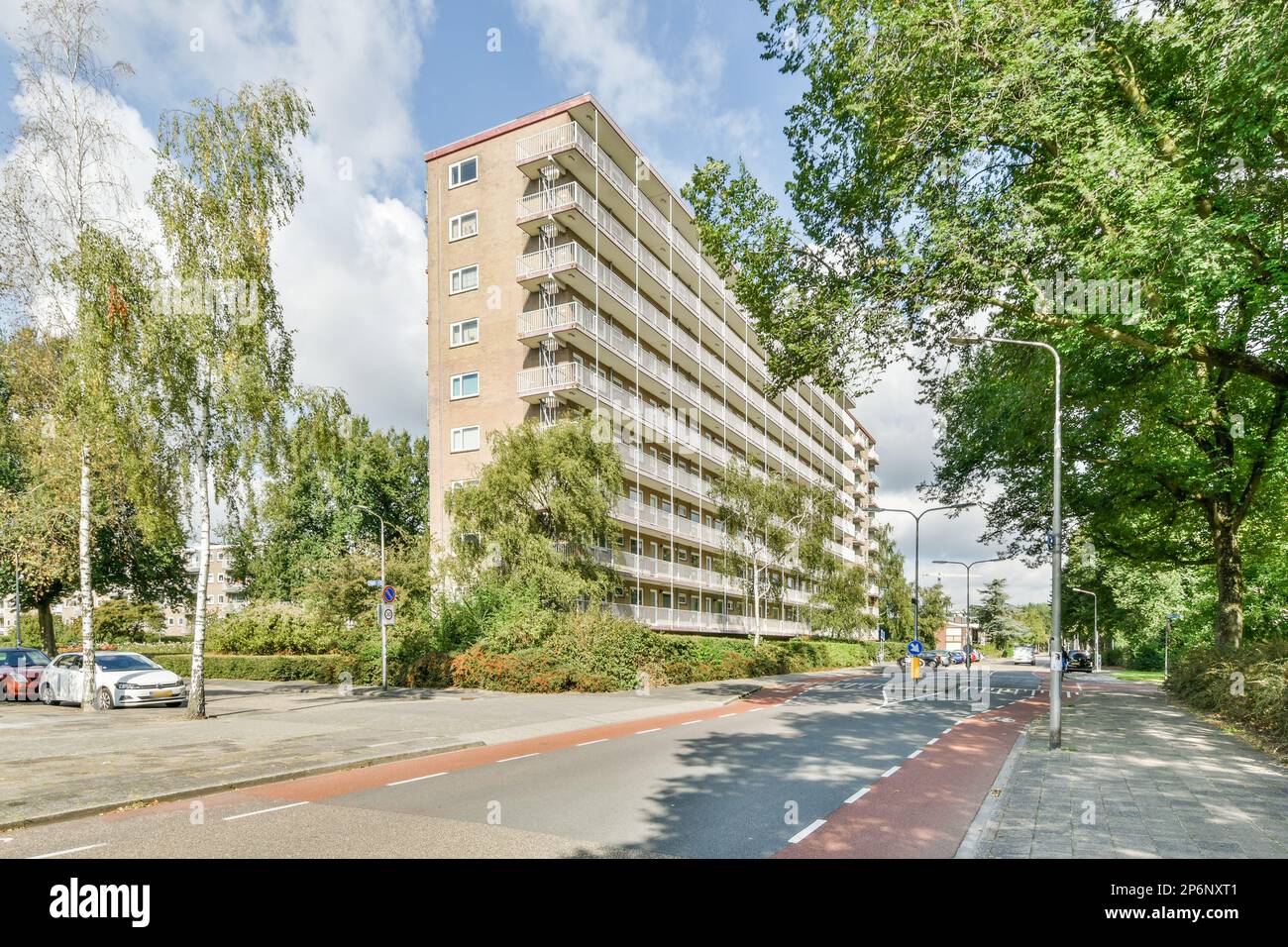 an apartment building on the side of a road with cars parked in front ...