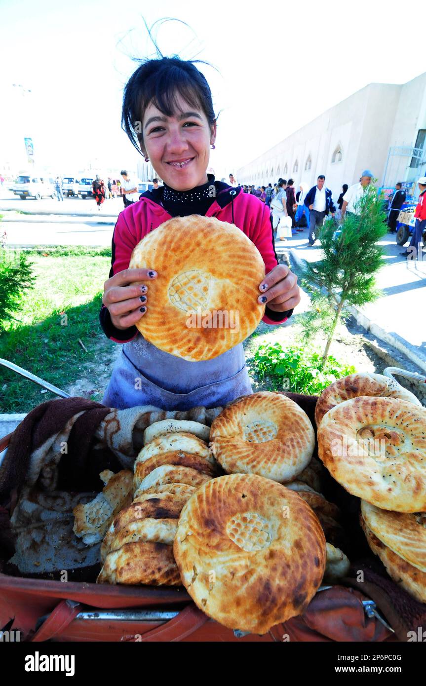 An Uzbek woman selling Obi Non- a traditional Uzbek / Tajik bread sold at the market in Bukhara, Uzbekistan. Stock Photo