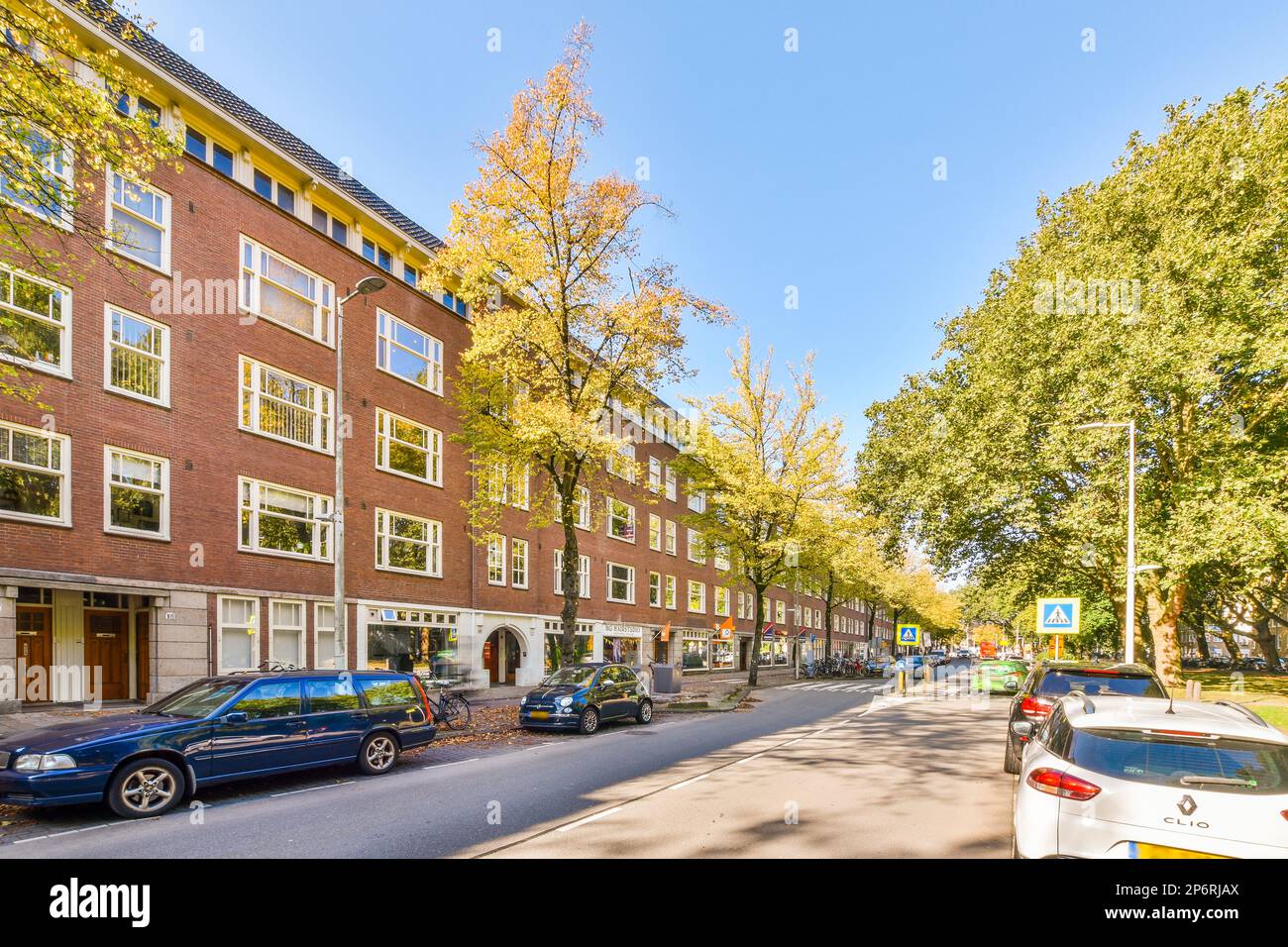 a city street with cars parked on the side and trees lining the street ...