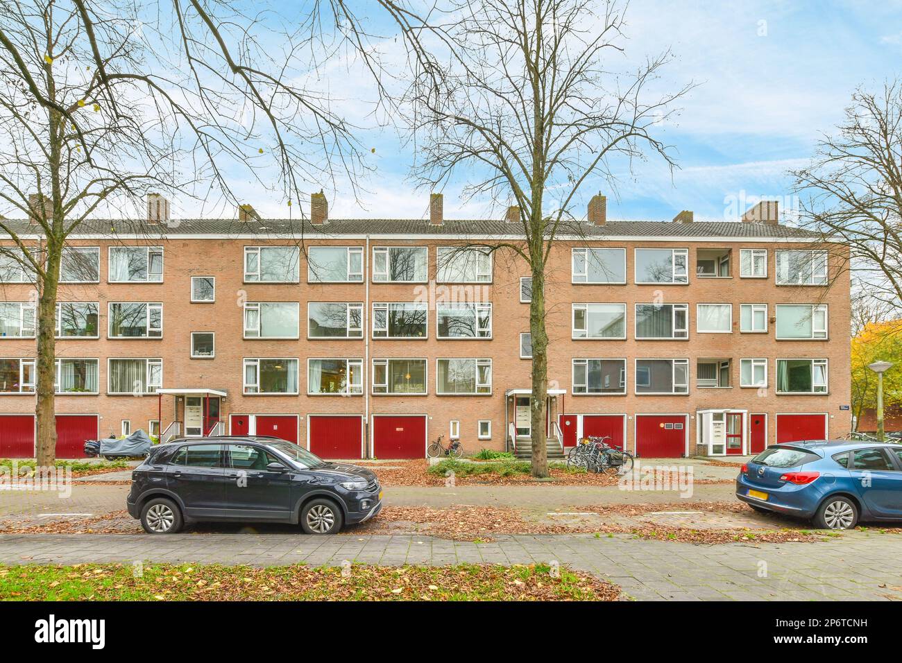 two cars parked in front of a row of brick apartment buildings with red ...