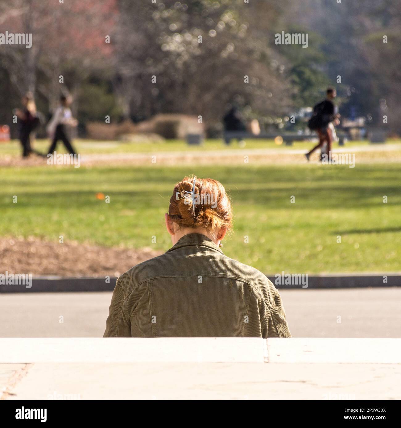 Red haired Duke University coed sitting on steps reading, head down
