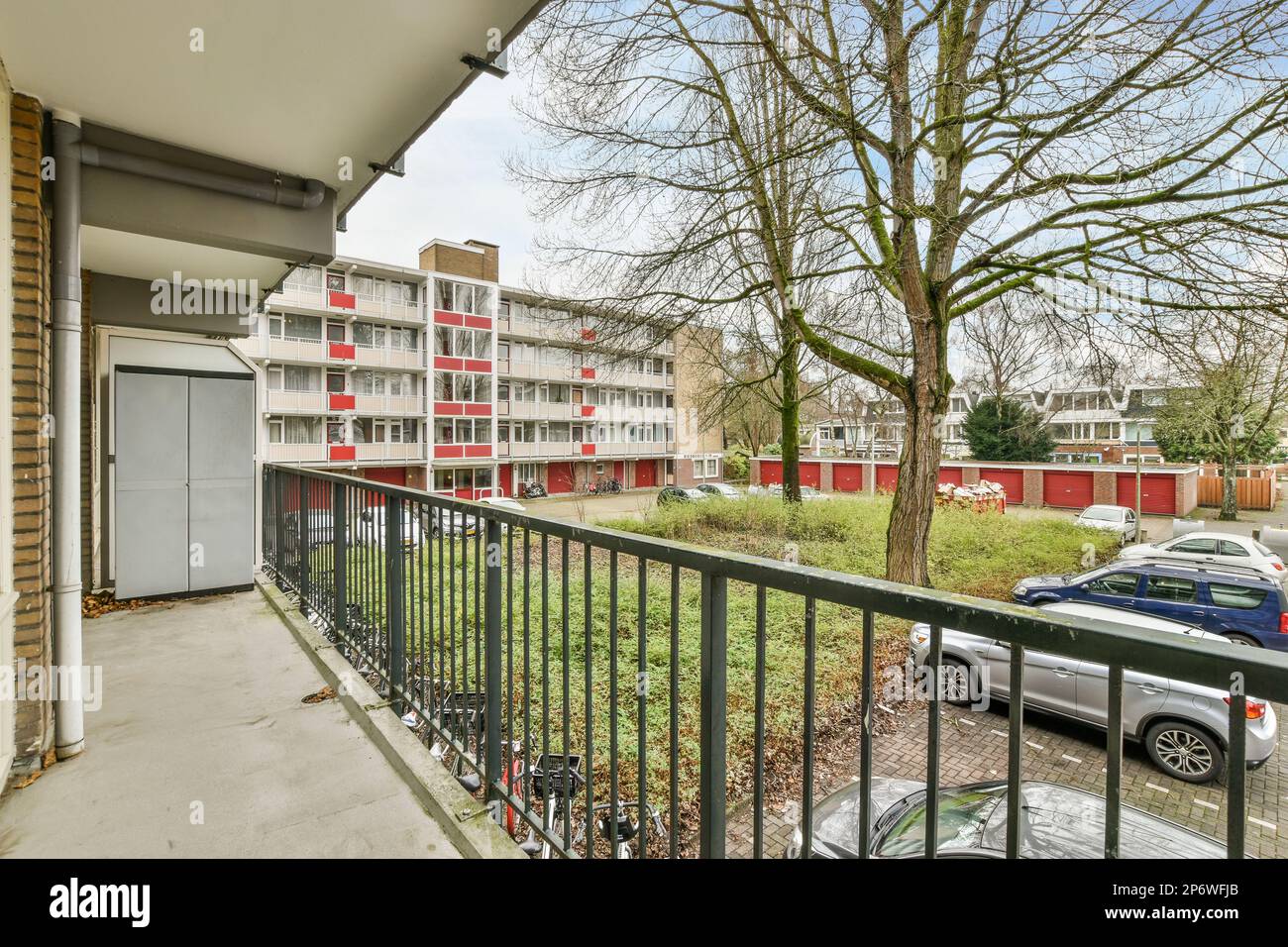 Amsterdam, Netherlands - 10 April, 2021: an outside area with cars parked in the parking lot and trees on the other side of the building, as seen from the balcony Stock Photo