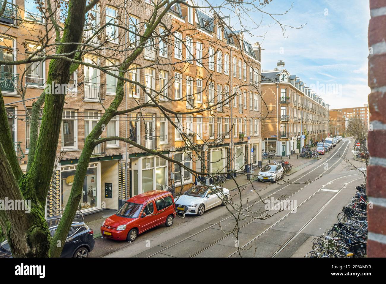 a city street with cars parked on the side and bicycles parked in front ...