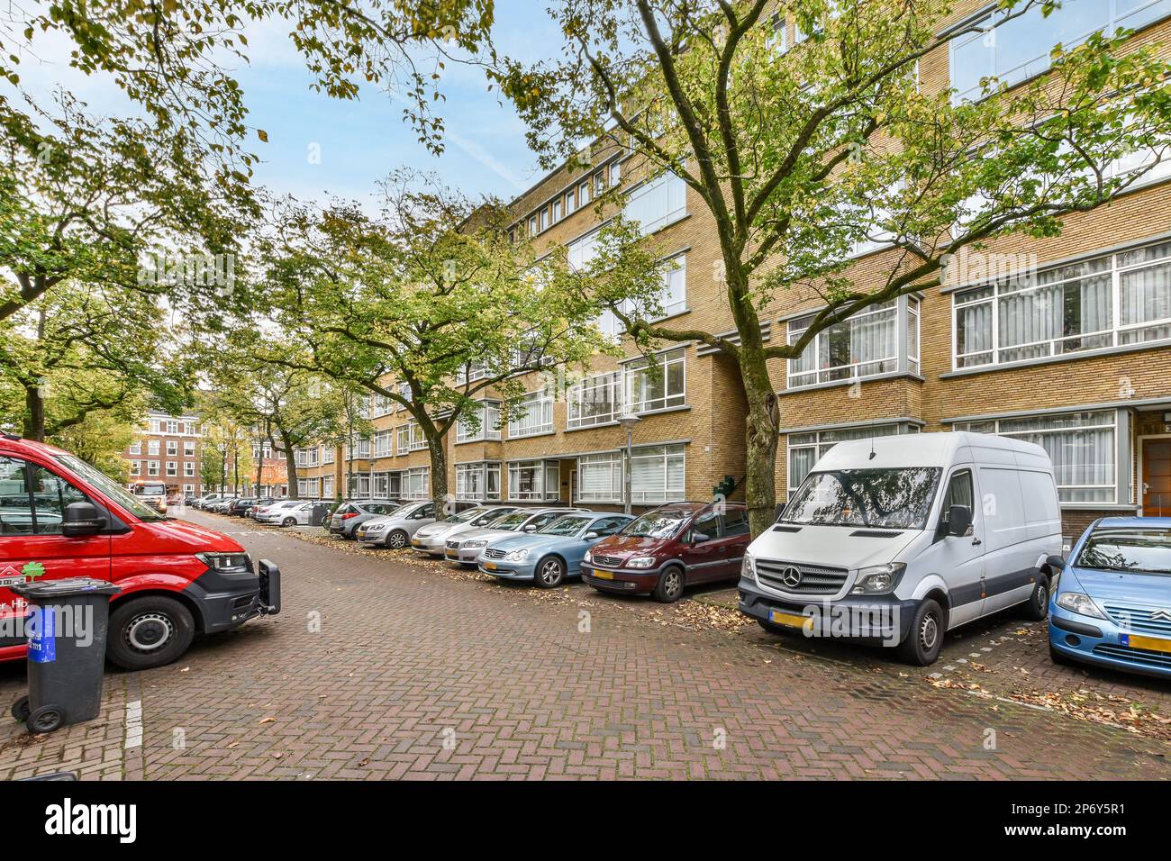 some cars parked on the side of a street in front of a row of brick ...