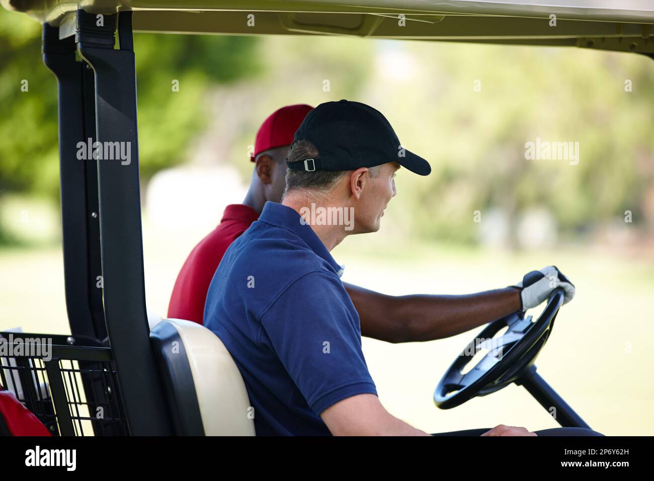 Carting it around the course. Profile of two men driving a golf cart on