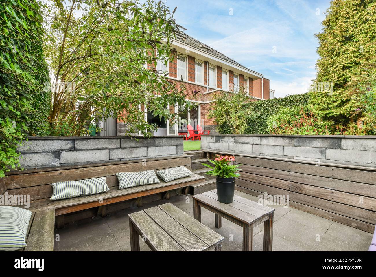 a patio with wooden benches and plants on the outside wall, in front of ...