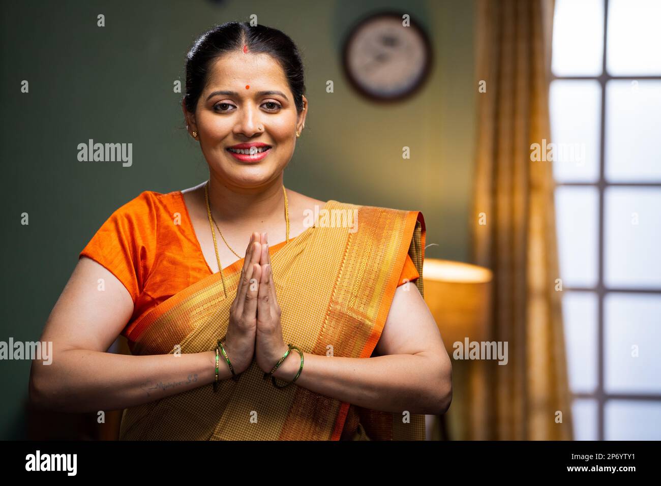 Happy smiling woman doing namaste or greeting by looking at camera - concept of welcome gesture, respect and gratitude Stock Photo