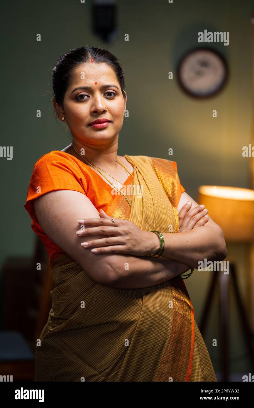 vertical shot of Confident woman standing confidently with arms crossed by looking at camera at home - concept of successful, family responsibility Stock Photo
