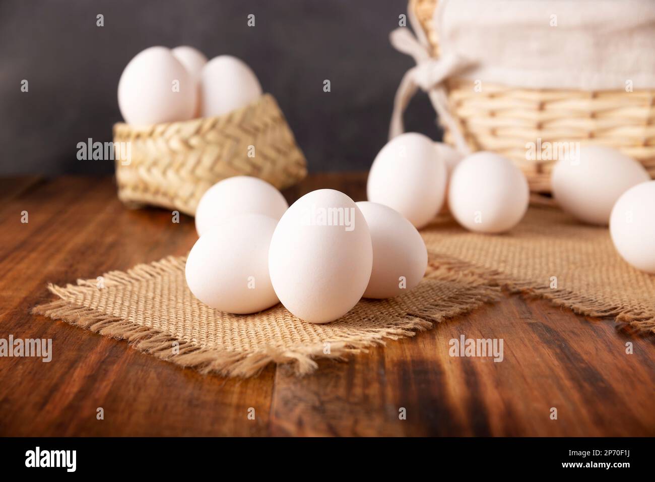 Many white chicken eggs on rustic wooden table. Very popular nutritious and economic food product. Stock Photo