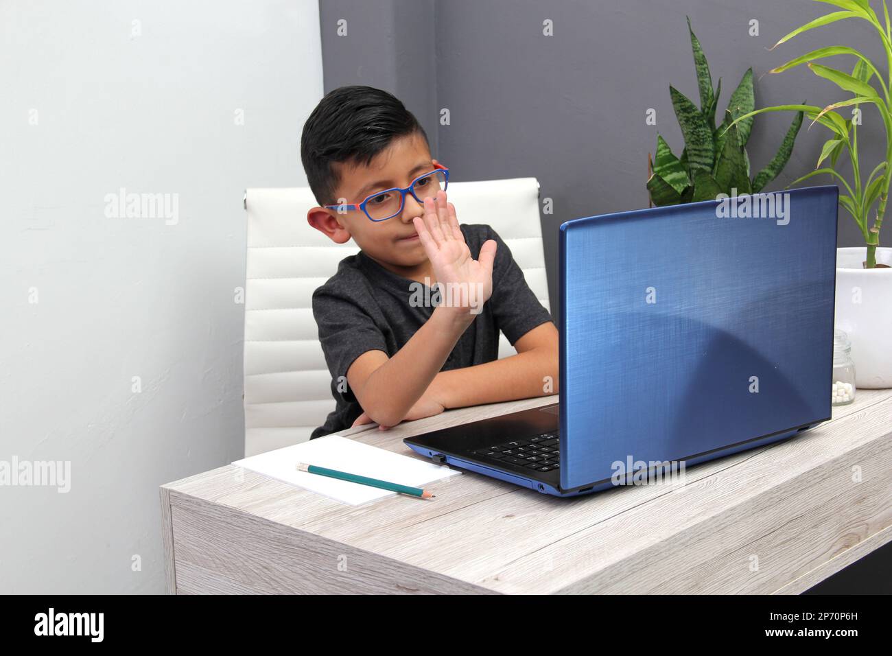 7yearold Latino boy with glasses does home schooling takes online