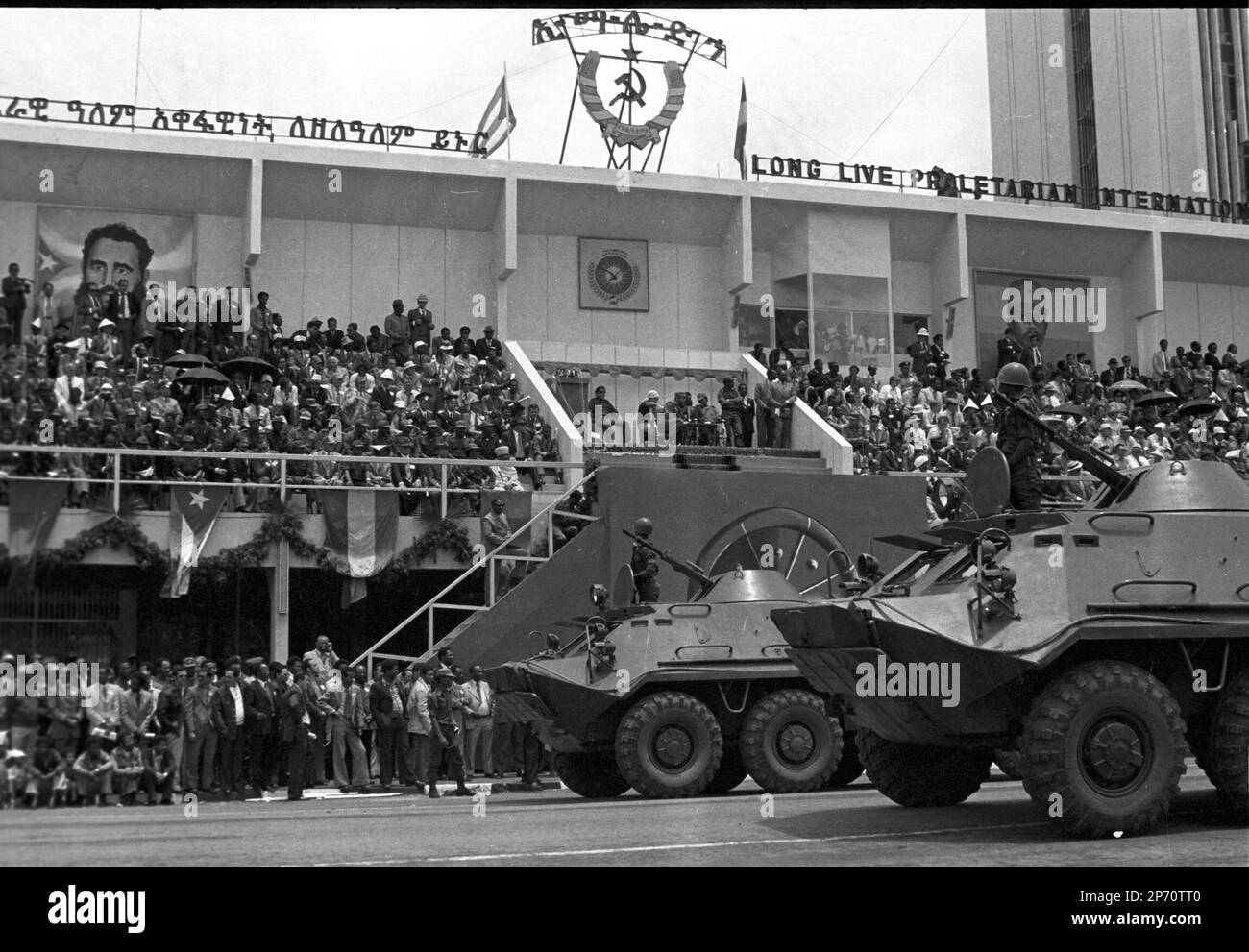 Armed vehicles ride past the reviewing stand in a parade commemorating