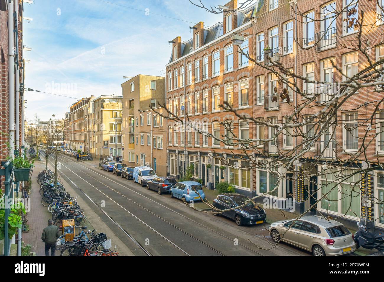 a city street with cars parked on the side and people walking down the ...