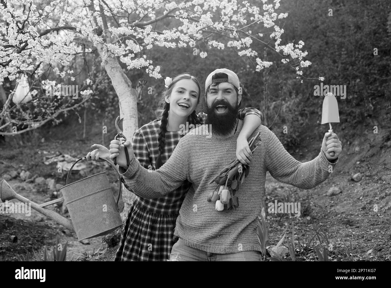 Funny gardener couple holding garden tools at spring nature background ...