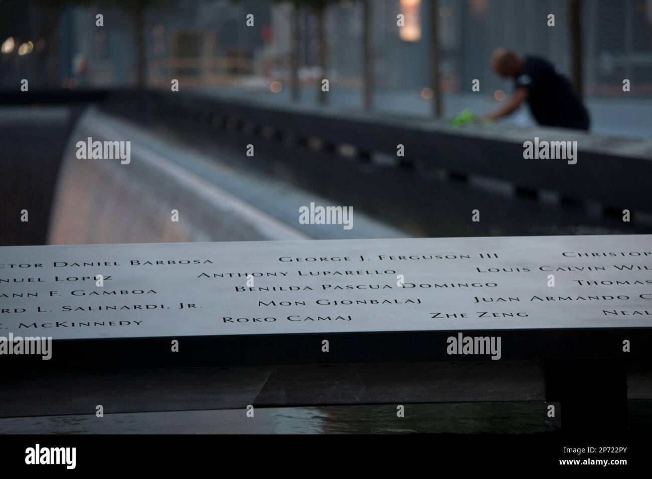 A man looks at names that surround one of the reflecting pools before