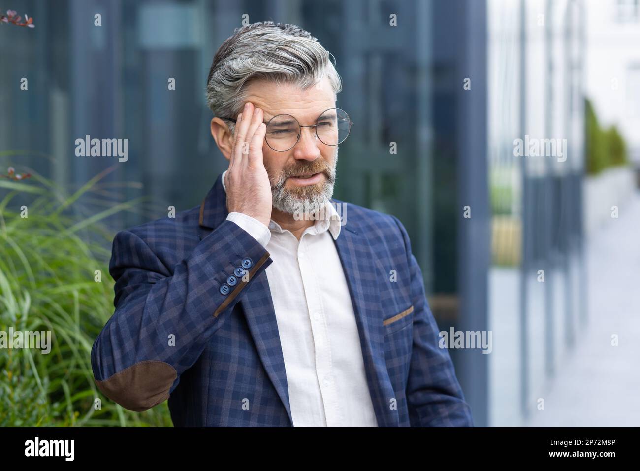 Sick and sad mature businessman outdoors sitting on bench on office ...