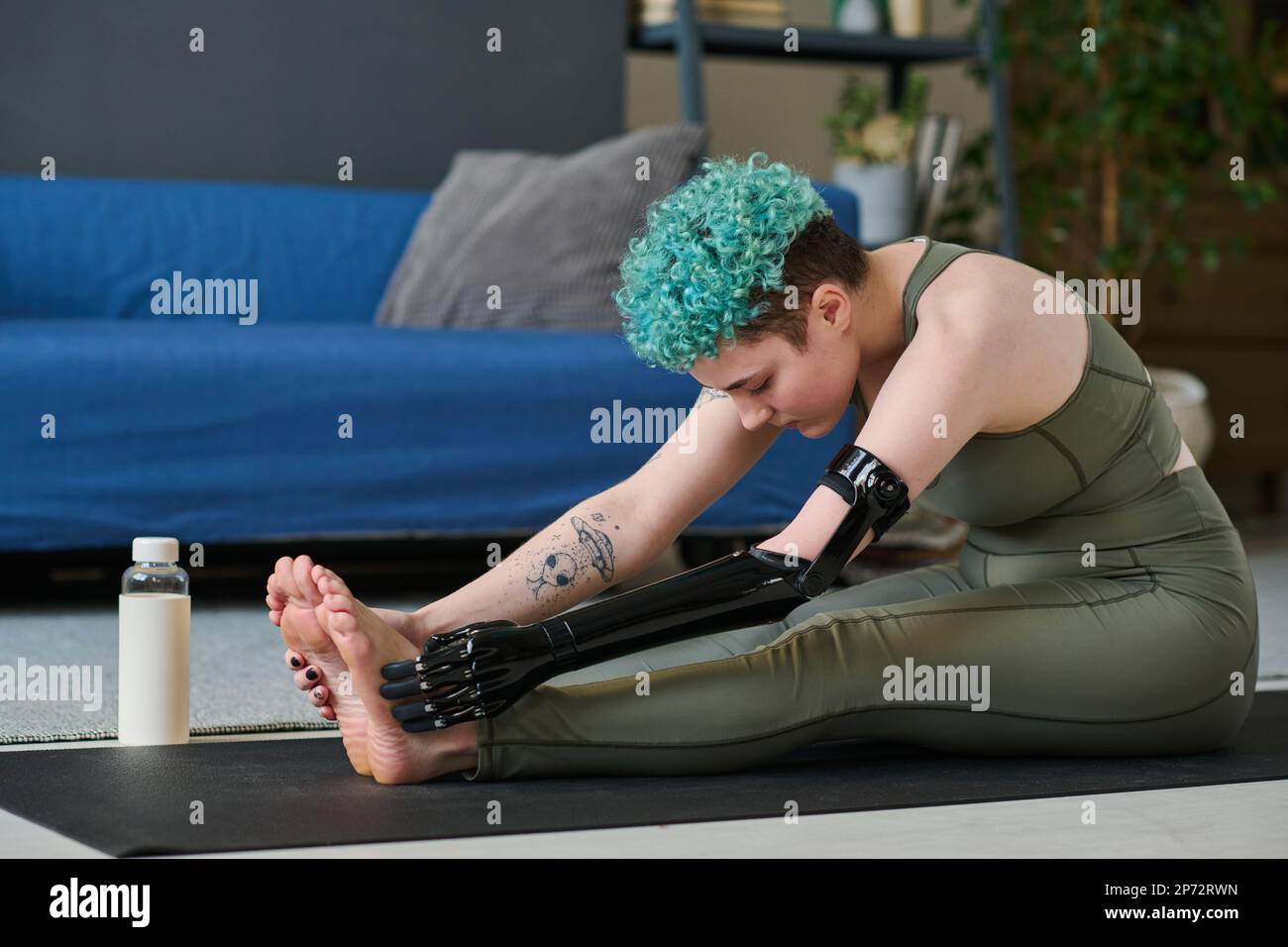 Woman with prosthetic arm exercising on exercise mat during training at home Stock Photo