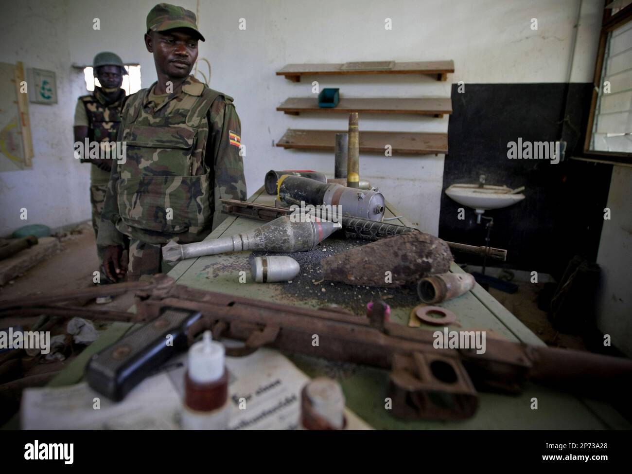 In a handout photograph released by the African Union-United Nations Information Support Team Monday, Aug.15, 2011, Ugandan soldiers serving with the African Union Mission in Somalia (AMISOM) sort through a bag of hand grenades and other munitions that were used by the extremist group Al Shabaab to make improvised explosive devices. AMISOM troops and Transitonal Federal Government (TFG) forces dislodged remnants of Al Shabaab from the site following the withdrawal of most of the extremist group's forces from the city ten days ago, discovering the bomb making facility at the former steel factor Stock Photo