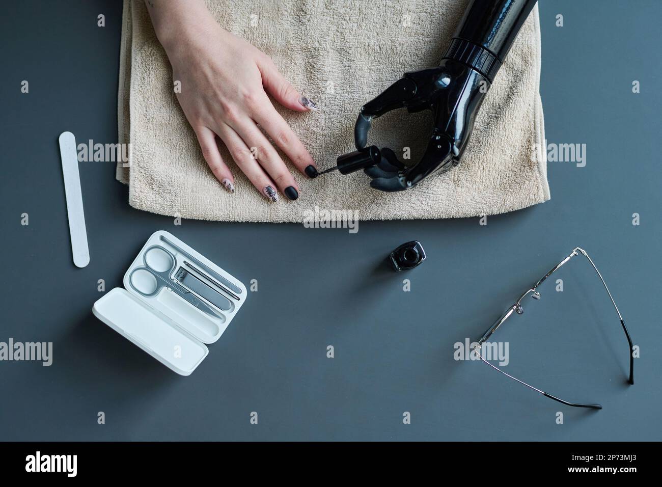 High angle view of young woman with prosthetic arm painting her nails with varnish Stock Photo