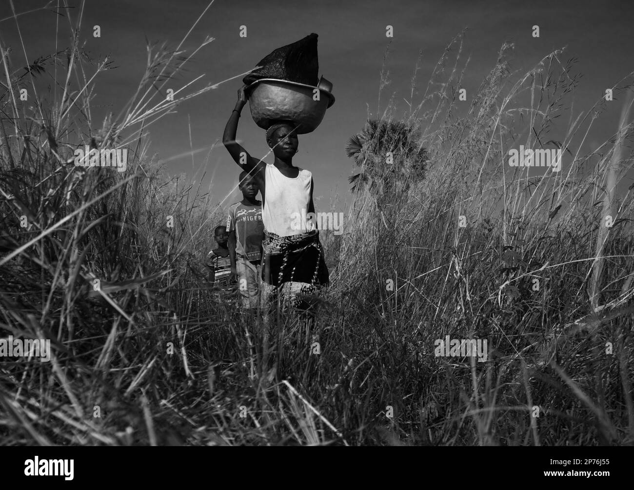 Mother and two sons walking through tall grass in North Benin, Basin on