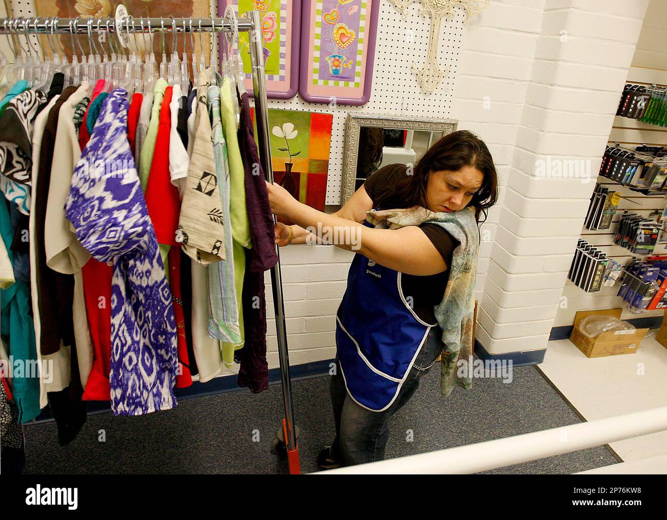 Goodwill Stocking Racks Faith Deal wheels racks of clothing up a ramp while stocking the new ...