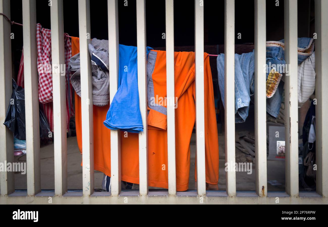 Clothes on a line stretched behind a steel security bars in Phnom Penh, Cambodia. Stock Photo