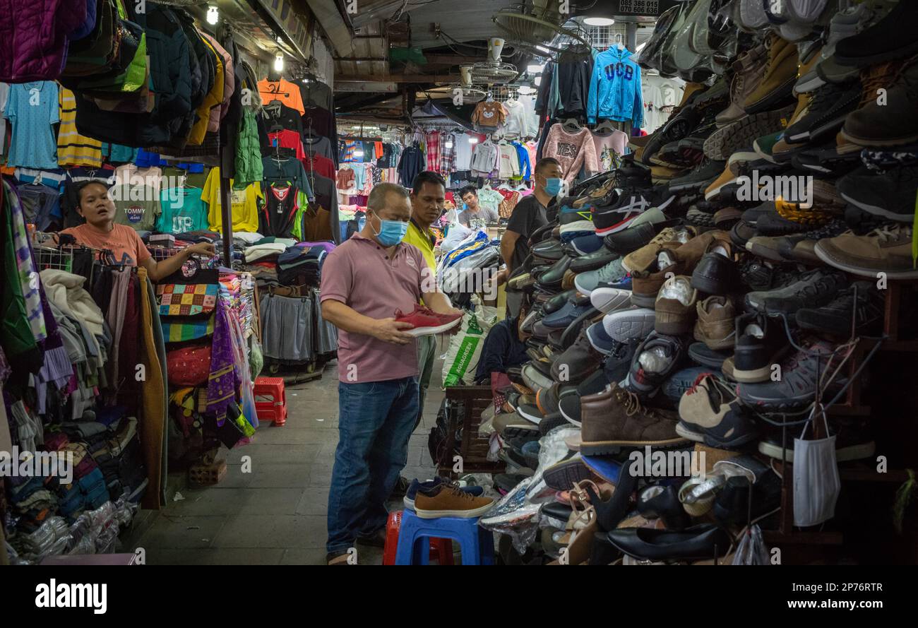 A middle-aged man looks at new trainers (sneakers) at a shoe stall wiithin the Russian Market in Phnom Penh, Cambodia. Stock Photo