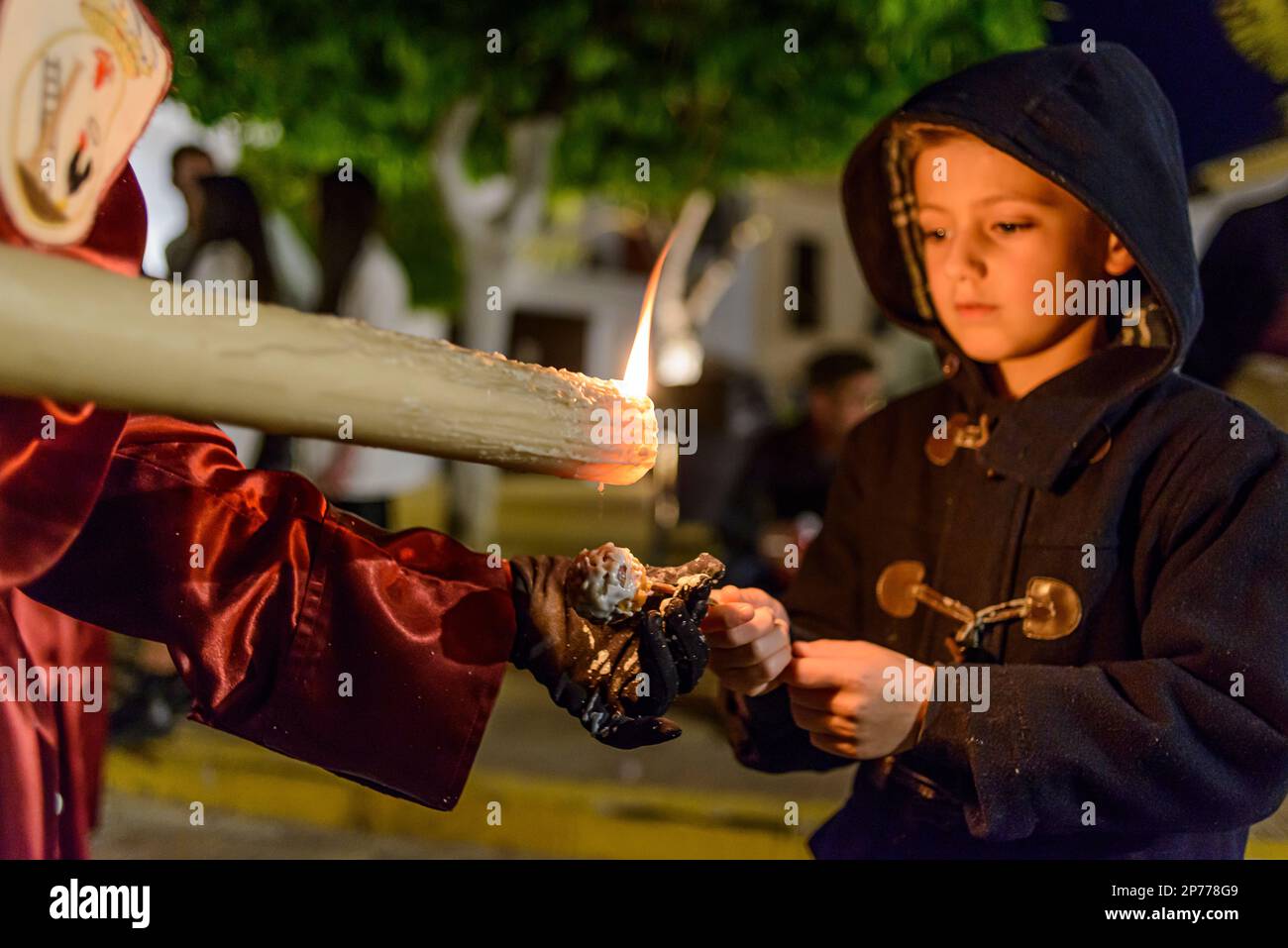 Arahal. Seville. Spain. 14th April, 2022. Child ask a penitent for wax to make a ball of wax. Penitential procession of the Brotherhood of La Miserico Stock Photo