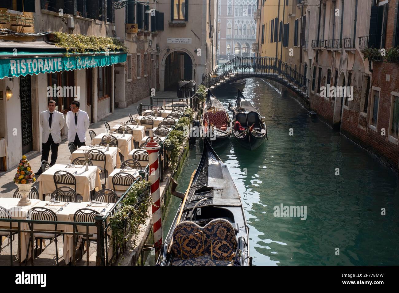 Waiters standing outside a canal side restaurant, Venice, Italy Stock Photo
