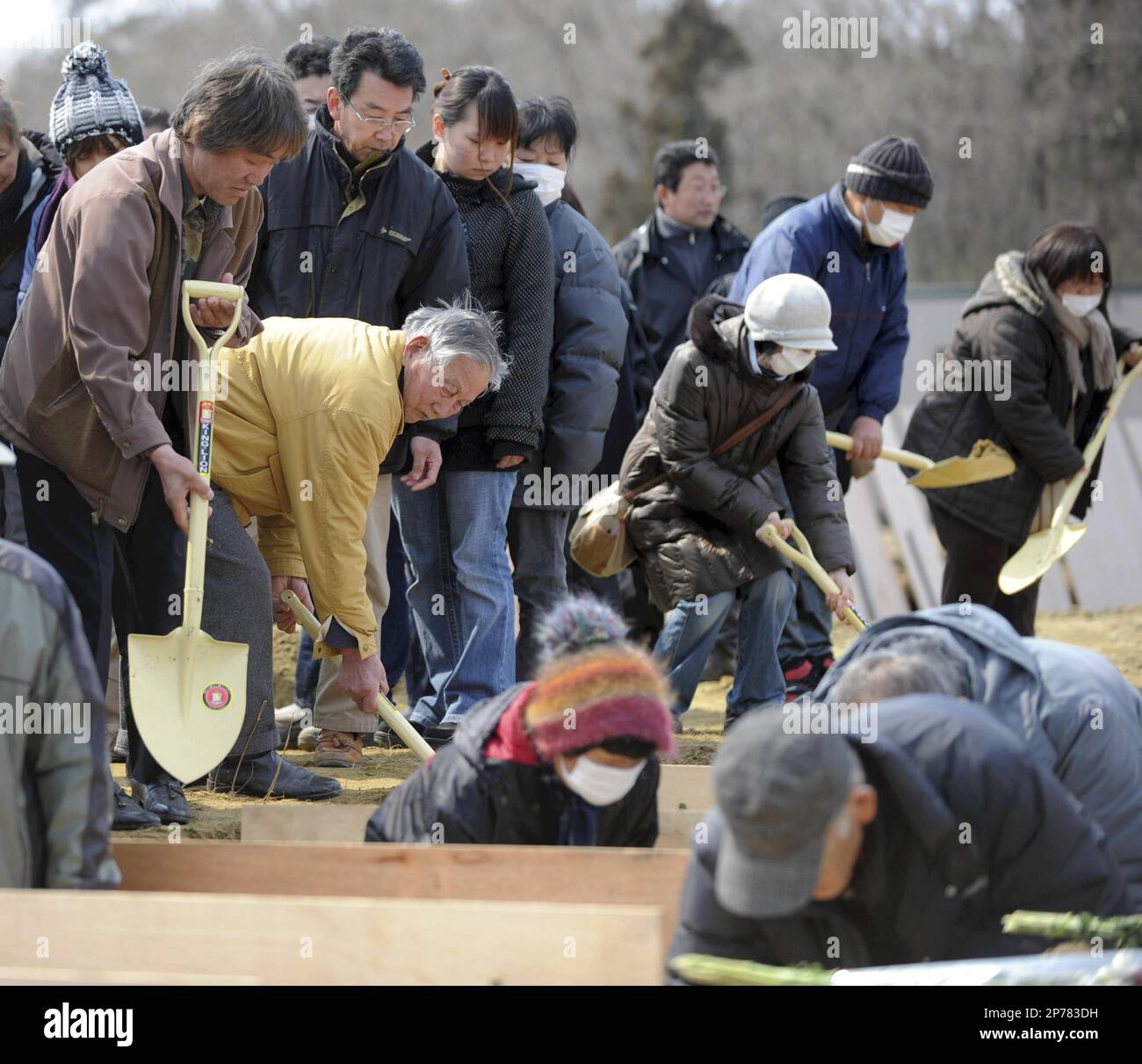 Family members and relatives throw dirt on a coffin at a burial site in