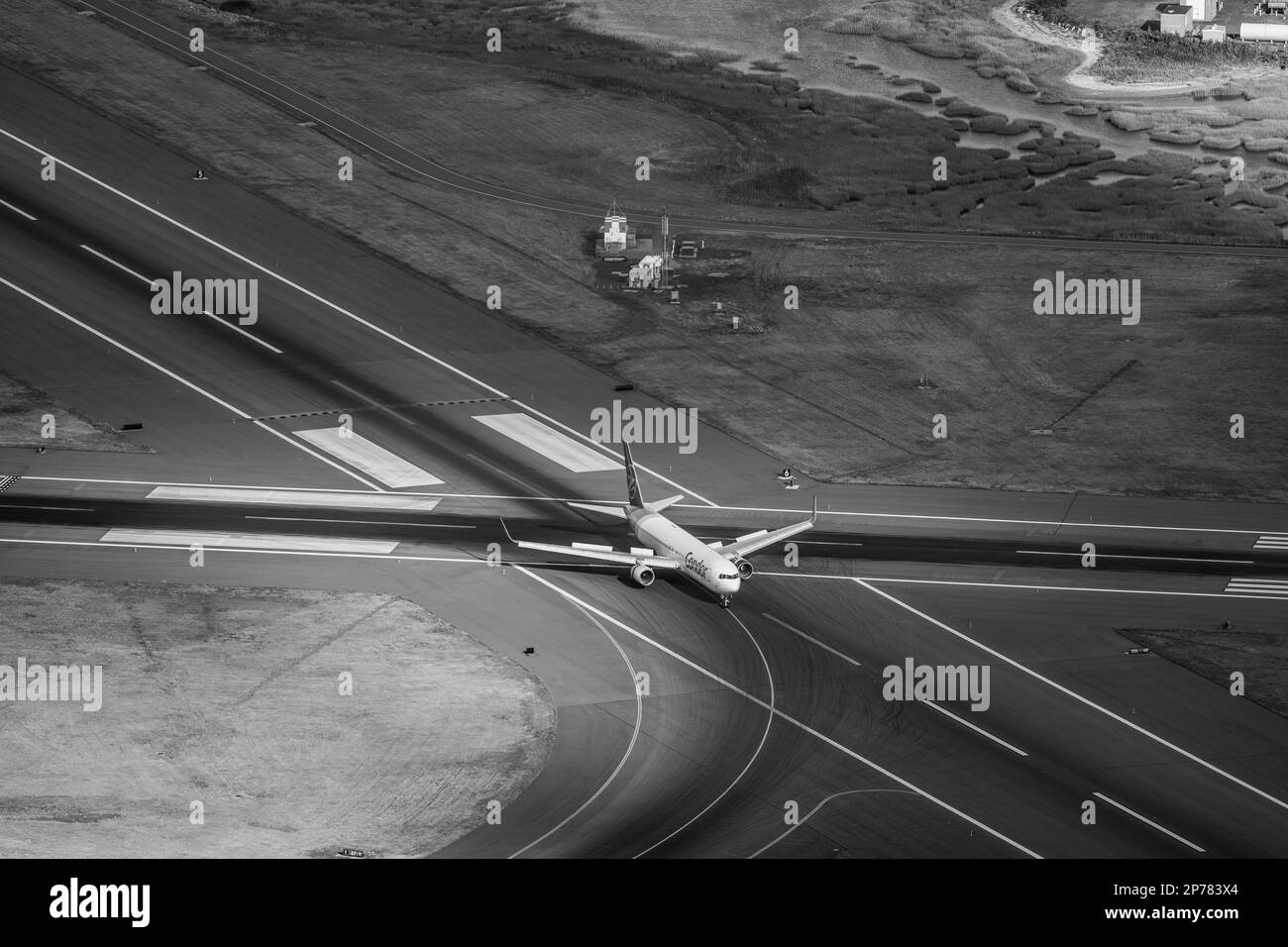 A grayscale shot of a Condor airplane taking off from a tarmac runway at an airport Stock Photo