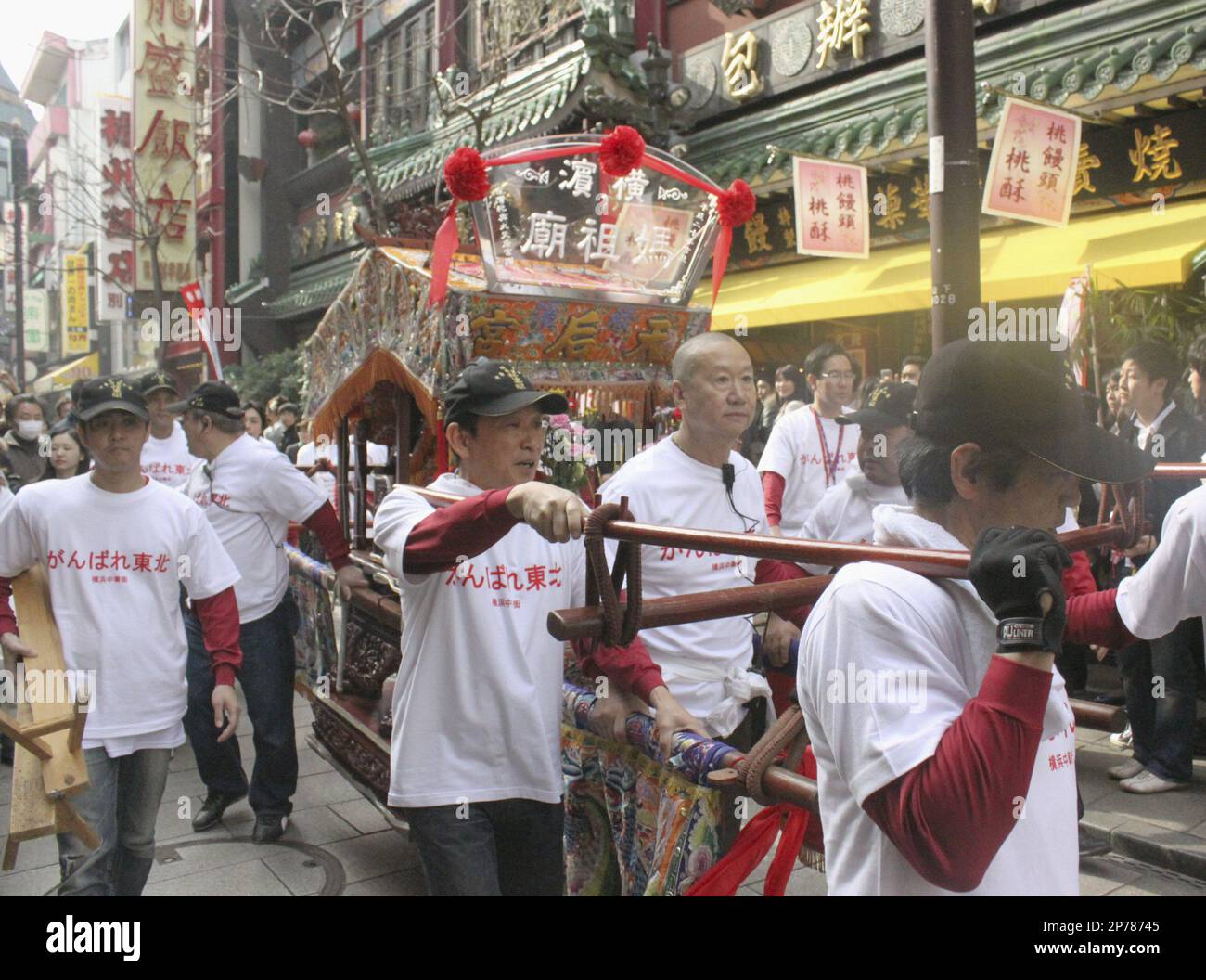 Wearing T-shirts with "Ganbare Tohoku, or Pep up Northeastern Japan" slogans, people parade through a street in Chinatown in Yokohama, near Tokyo, carrying a portable shrine of Mazu, or tin Hau, the Goddess of the Sea, celebrating the birth of the goddess, also known as the guardian of disaster and illness, Sunday, March 20, 2011. This year people collected donations from onlookers for evacuees of March 11 earthquake and tsunami in northeastern Japan. (AP Photo/Kyodo News) JAPAN OUT, MANDATORY CREDIT, NO LICENSING IN CHINA, HONG KONG, JAPAN, SOUTH KOREA AND FRANCE Stock Photo