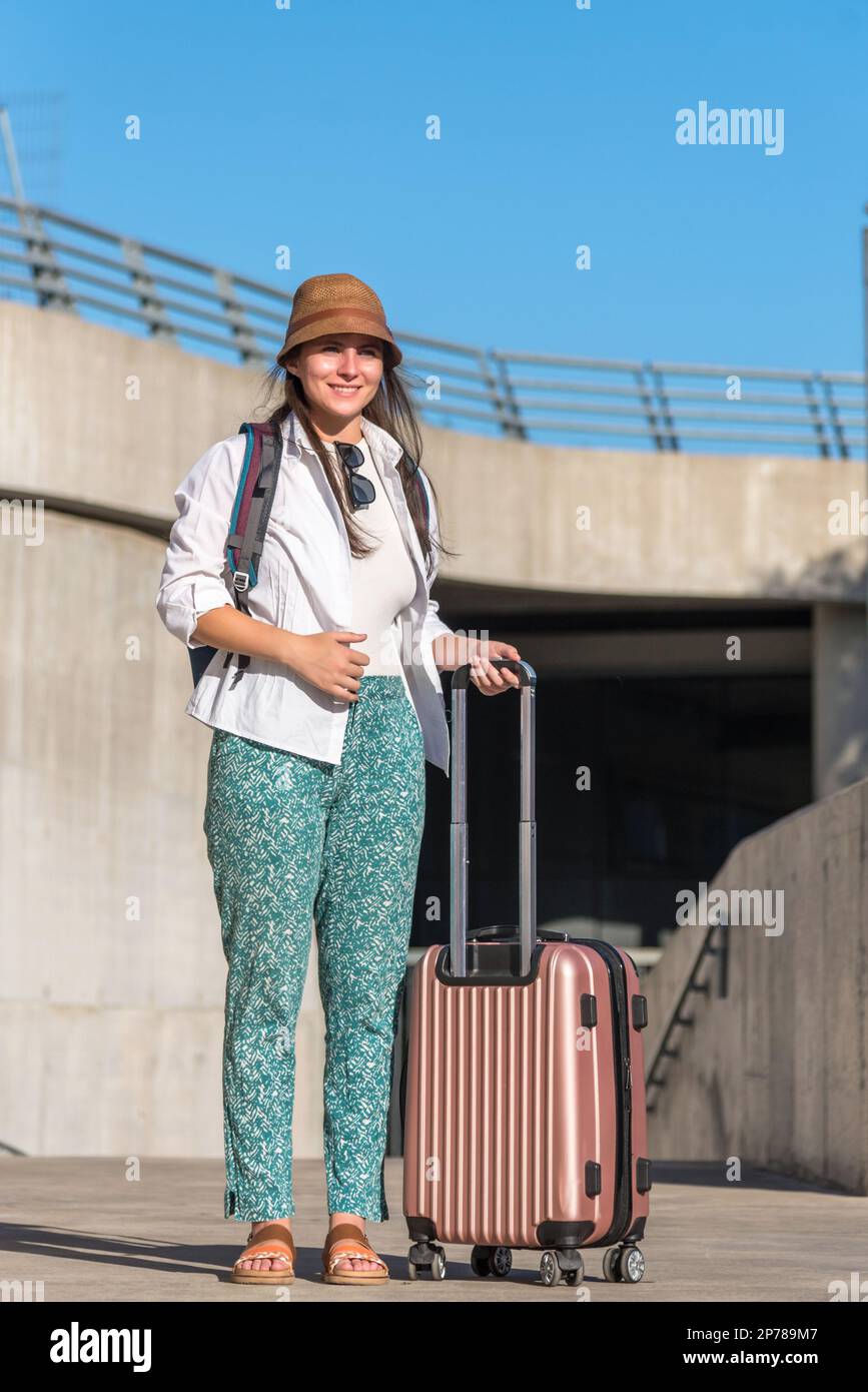 Female traveler smiling while standing outdoors with a suitcase Stock ...