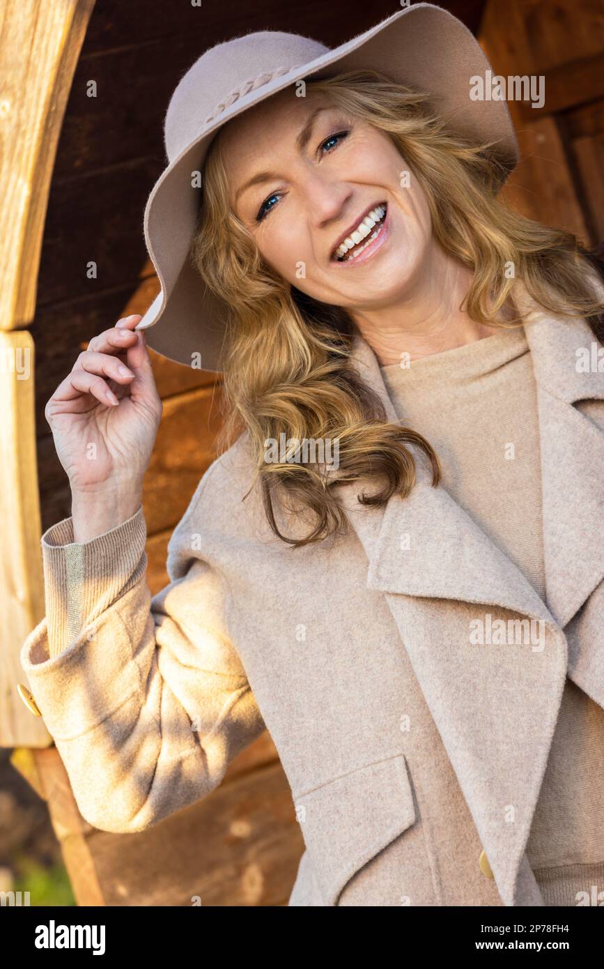 Attractive happy smiling stylish middle aged woman outside wearing a hat Stock Photo