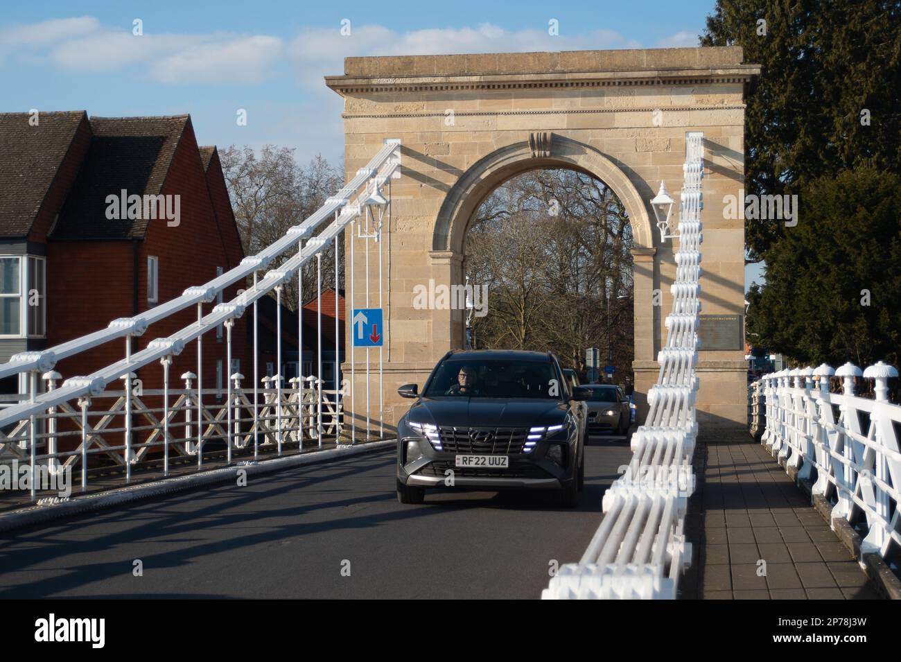 Marlow, Buckinghamshire, UK. 2nd March, 2023. Traffic crosses Marlow Suspension Bridge in Buckinghamshire. The bridge is a  Grade I Listed Building. Last year a petition was launched by locals to try to get the bollards on the bridge removed. They are there to stop HGVs crossing the bridge, however, many motorists have damaged their cars as they try to squeeze through the tight gap on the road lined by bollards. Credit: Maureen McLean/Alamy Stock Photo