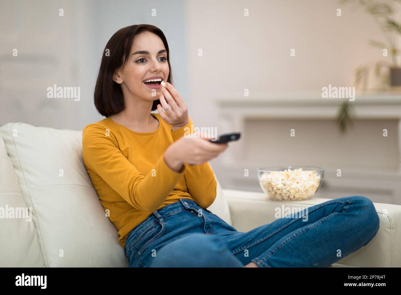 Happy young woman relaxing at home, watching TV Stock Photo